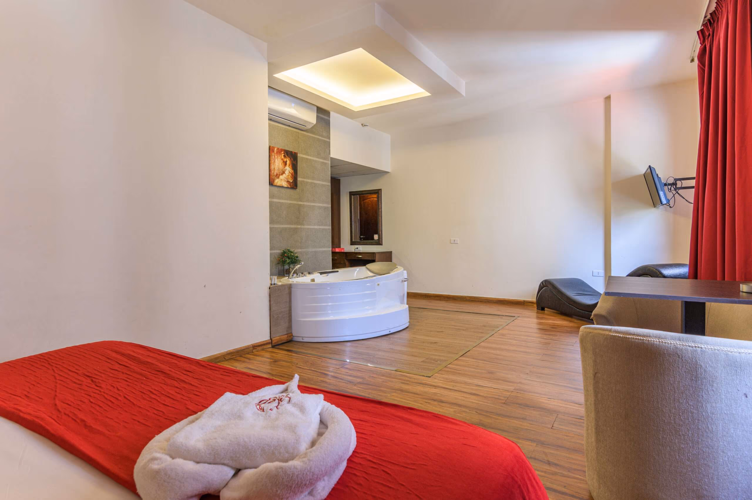 A suite with a corner whirlpool tub, a bed and a seating area