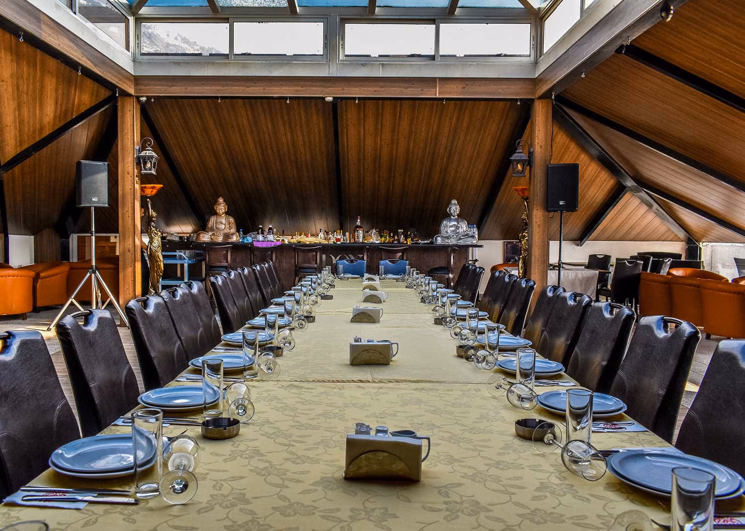 A long table laid for dinner beneath a pitched timber and glass ceiling