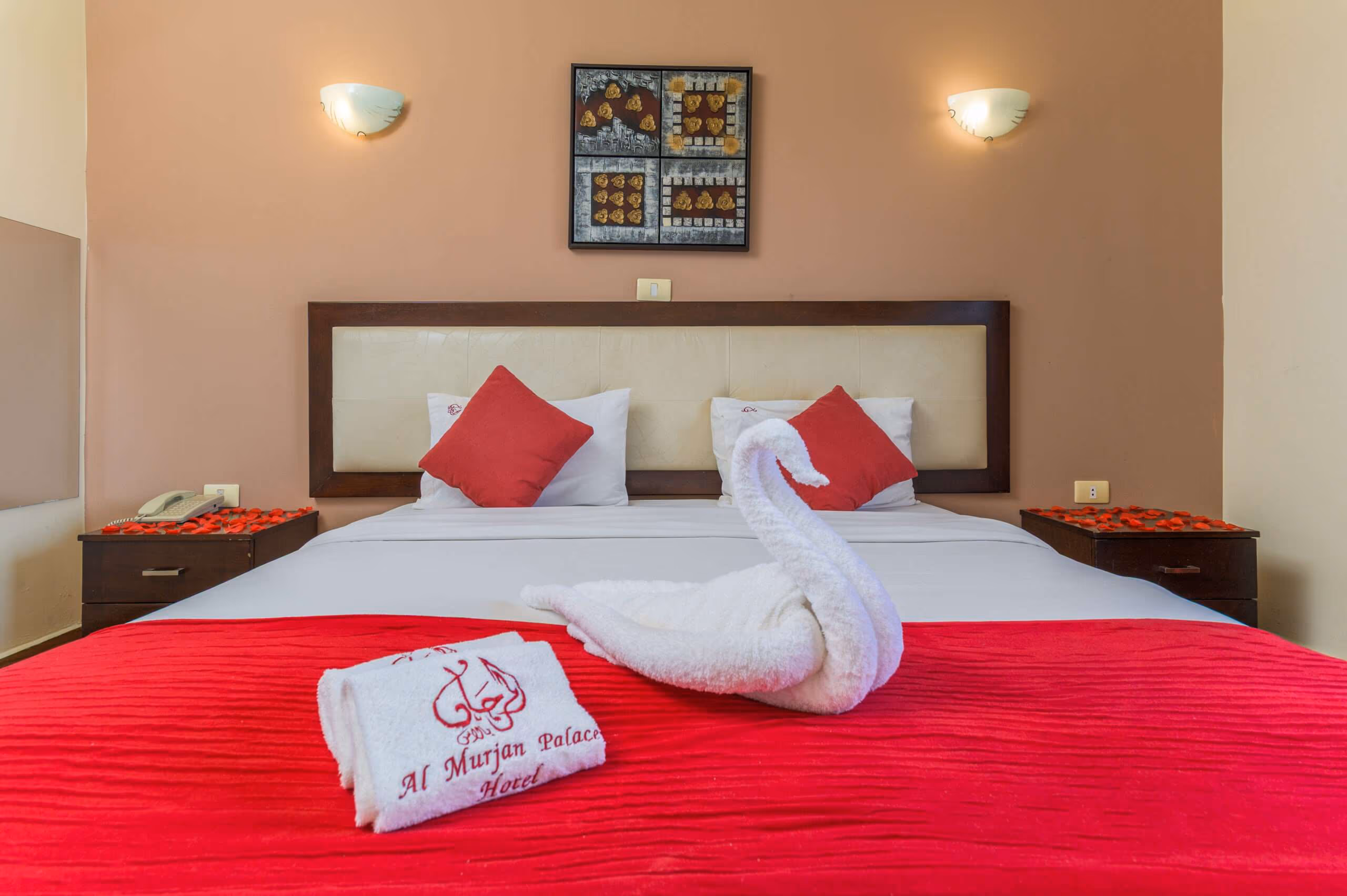 A room with two single beds made up in white and red, and a framed picture above