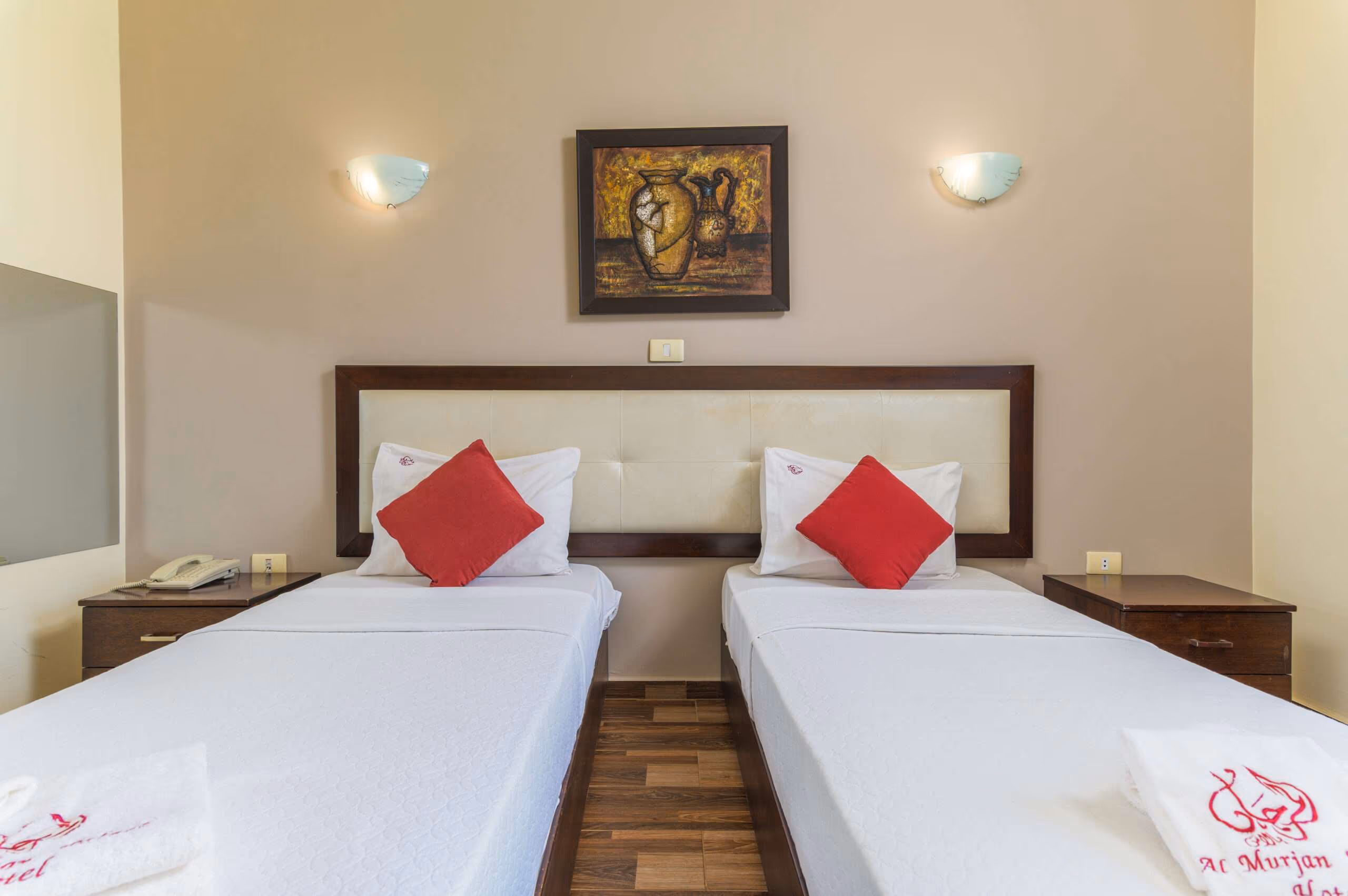A twin room with two beds, bedside lamps and a framed picture